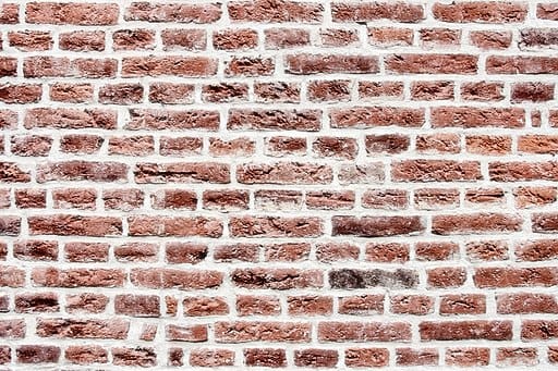 Photo of a brick wall. Earth reds, browns, and cream,