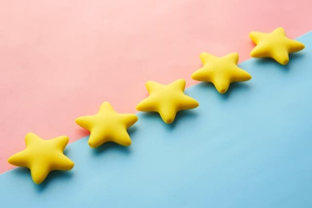 A rectangle shape, cut in half diagonally. The top half is pink. The bottom half is blue. Across the diagonal are five yellow stars lined up.