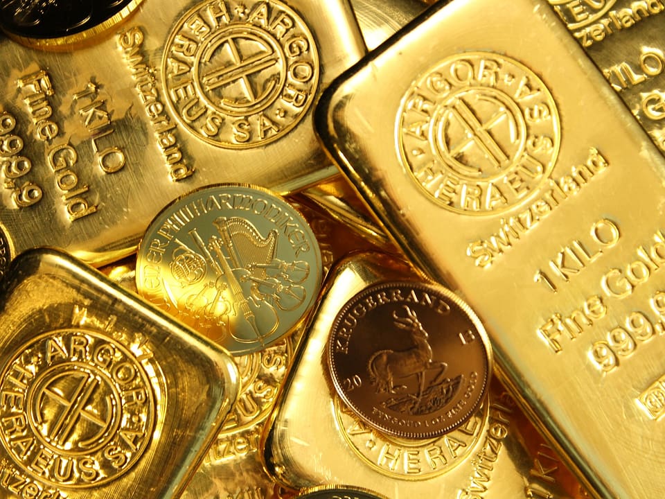 Bars of gold placed on top of each other, in a haphazard way, interspersed with gold coins. Bars stamped as 1 kilo from Switzerland.