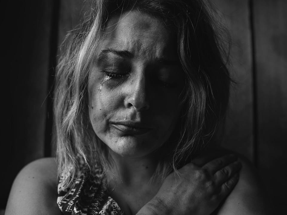 Black and white photo of women crying an ugly cry. Her white skin smudged with makeup and stringy, blonde highlighted hair. Her eyes are closed.
