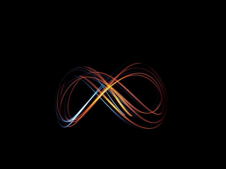 A multi-colored infinity symbol, with a black background. Colors of the spectrum are showing, lit up.