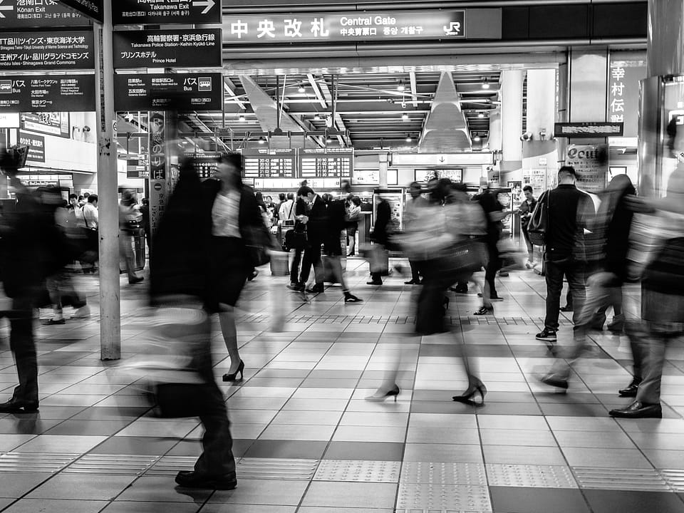 Black and white photo of busy commuters in Shinagawa railway station in Tokyo, Japan.